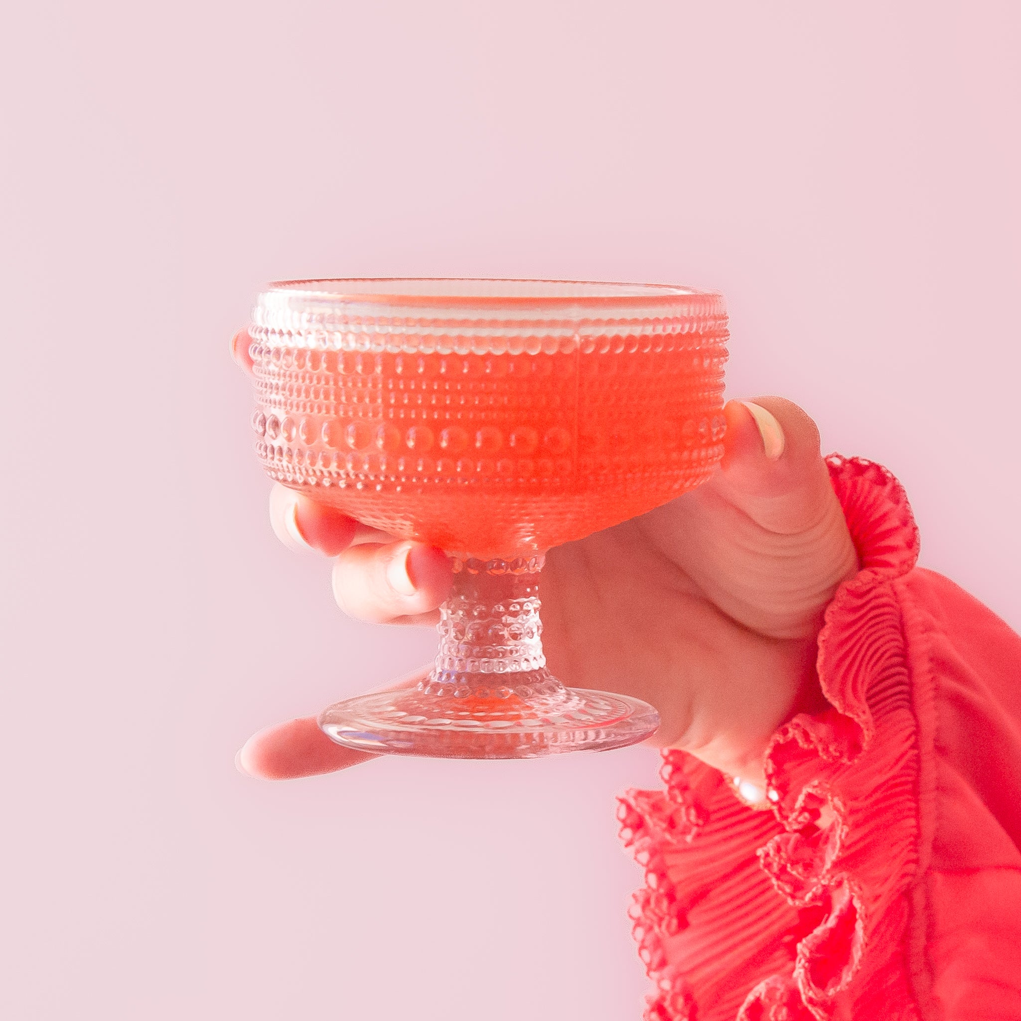 A light pink dot textured coupe drinking glass