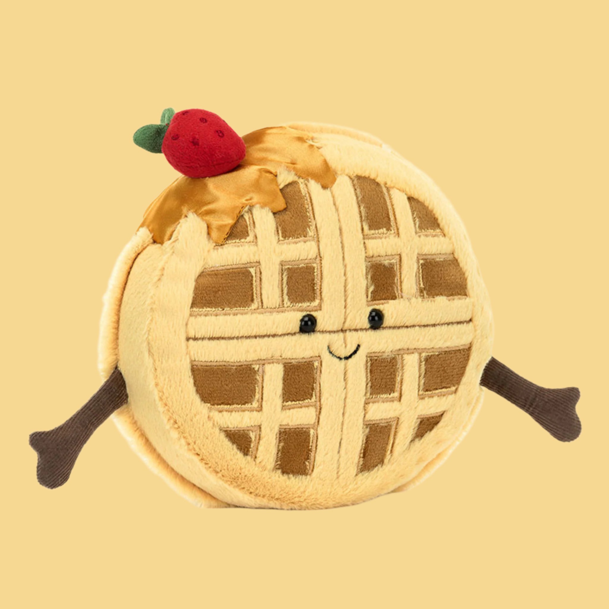 A waffle shaped stuffed toy with a strawberry on the top and a smiling face and arms. 