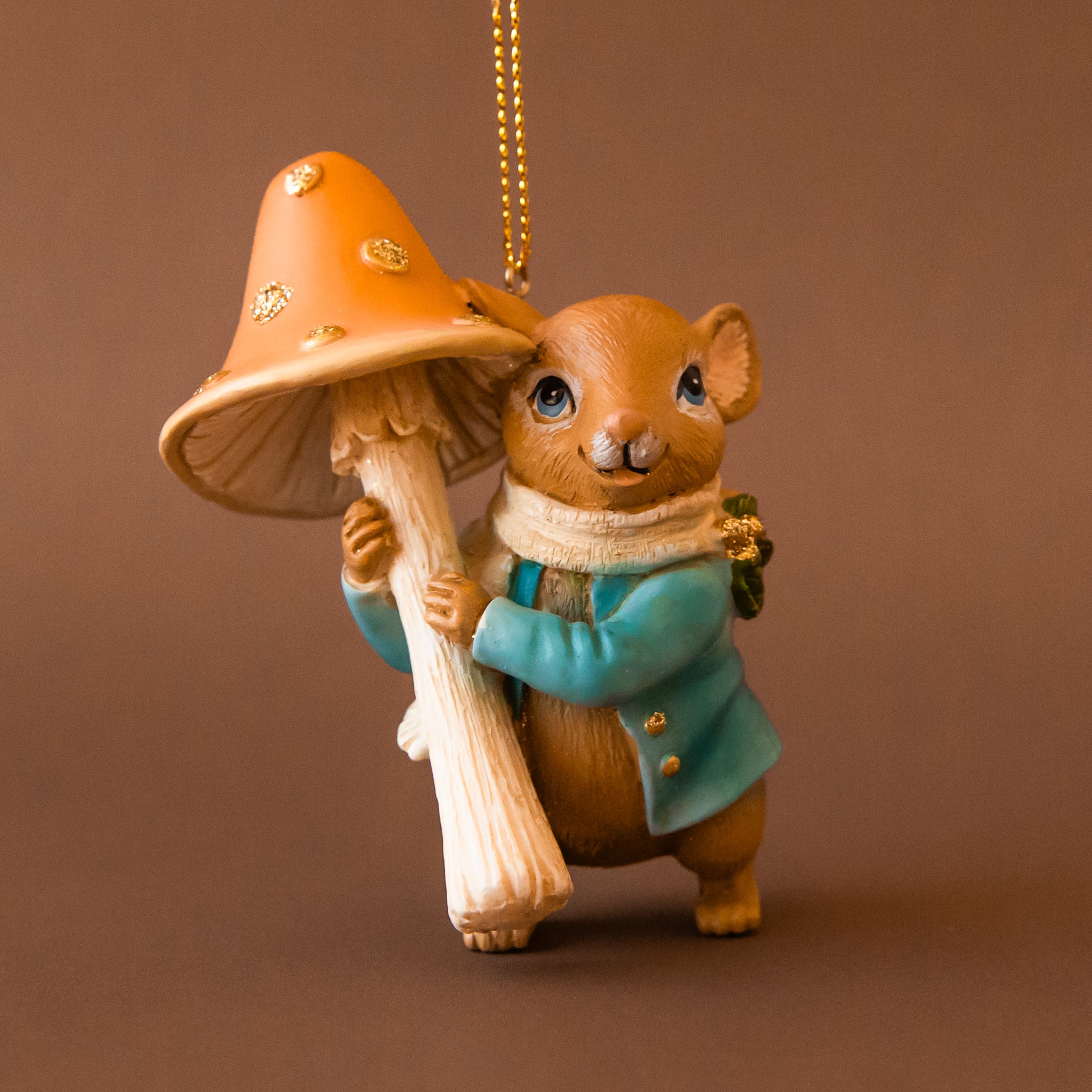 A mouse shaped ornament holding an orange mushroom. 