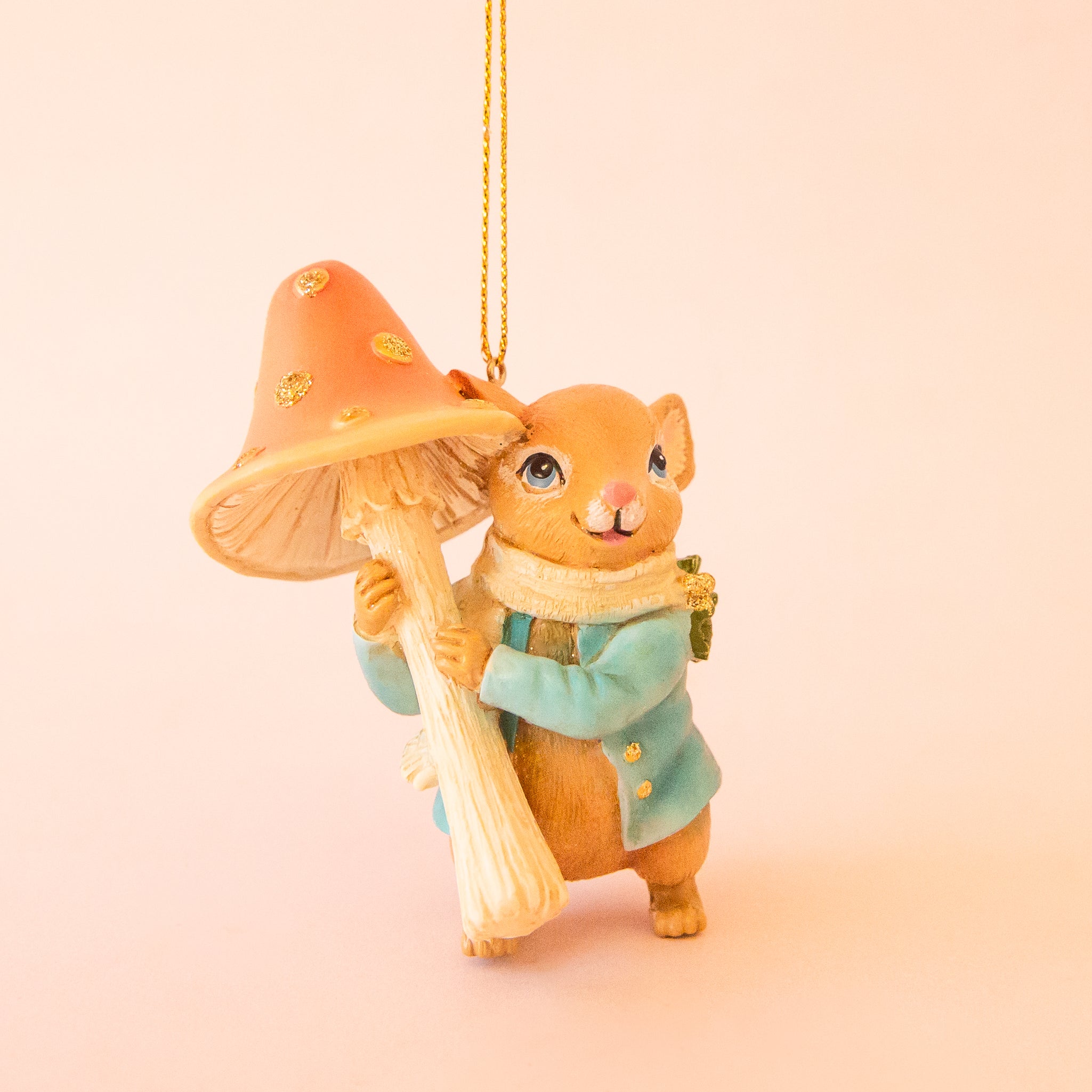 A mouse shaped ornament holding an orange mushroom. 