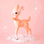 On a light orange background is a peachy pink colored retro deer figurine with white spot details and a gold bell at the front of its neck.