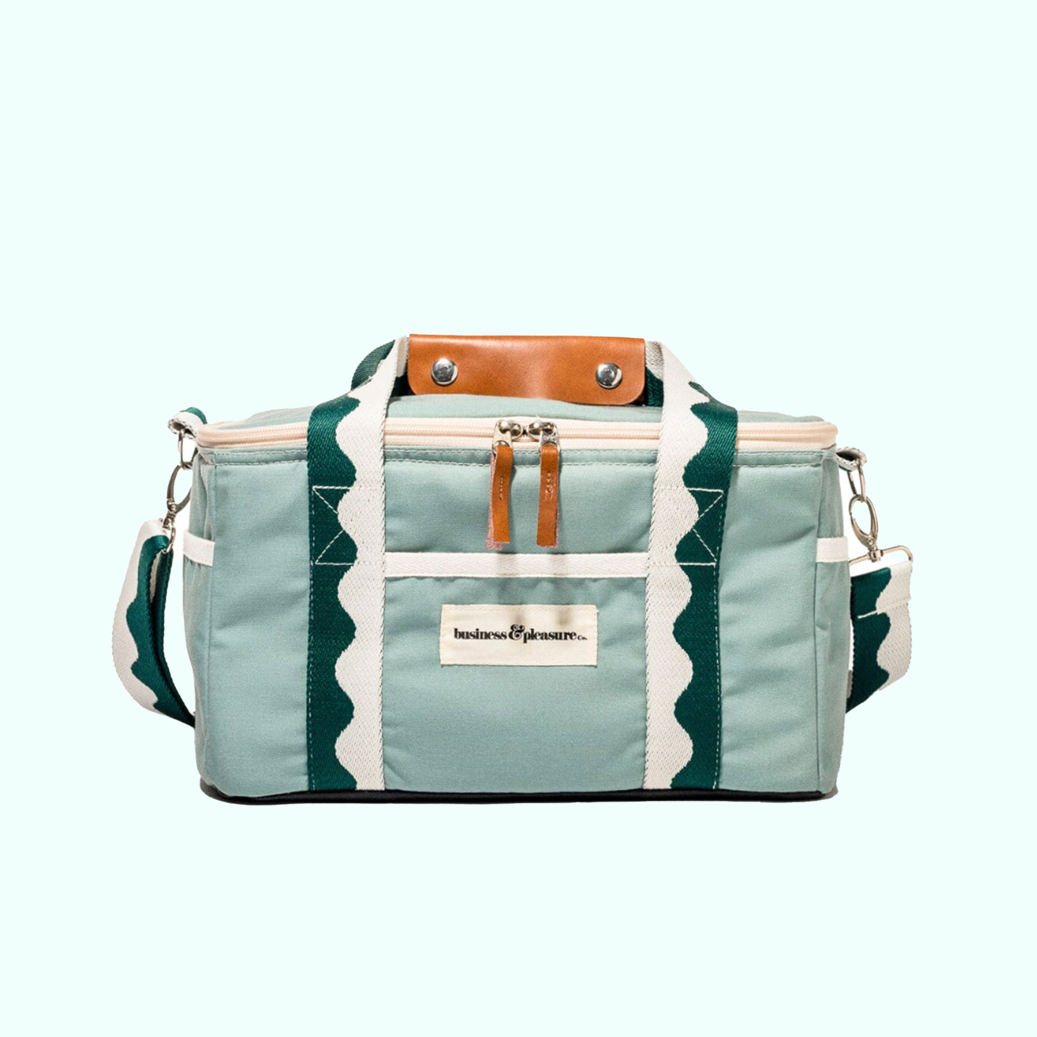 A green premium cooler bag with wavy dark green and white stripes and a label on the front that reads, "business & pleasure".