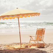 A white and yellow folding beach chair with a zip back pocket and a headrest pillow. 