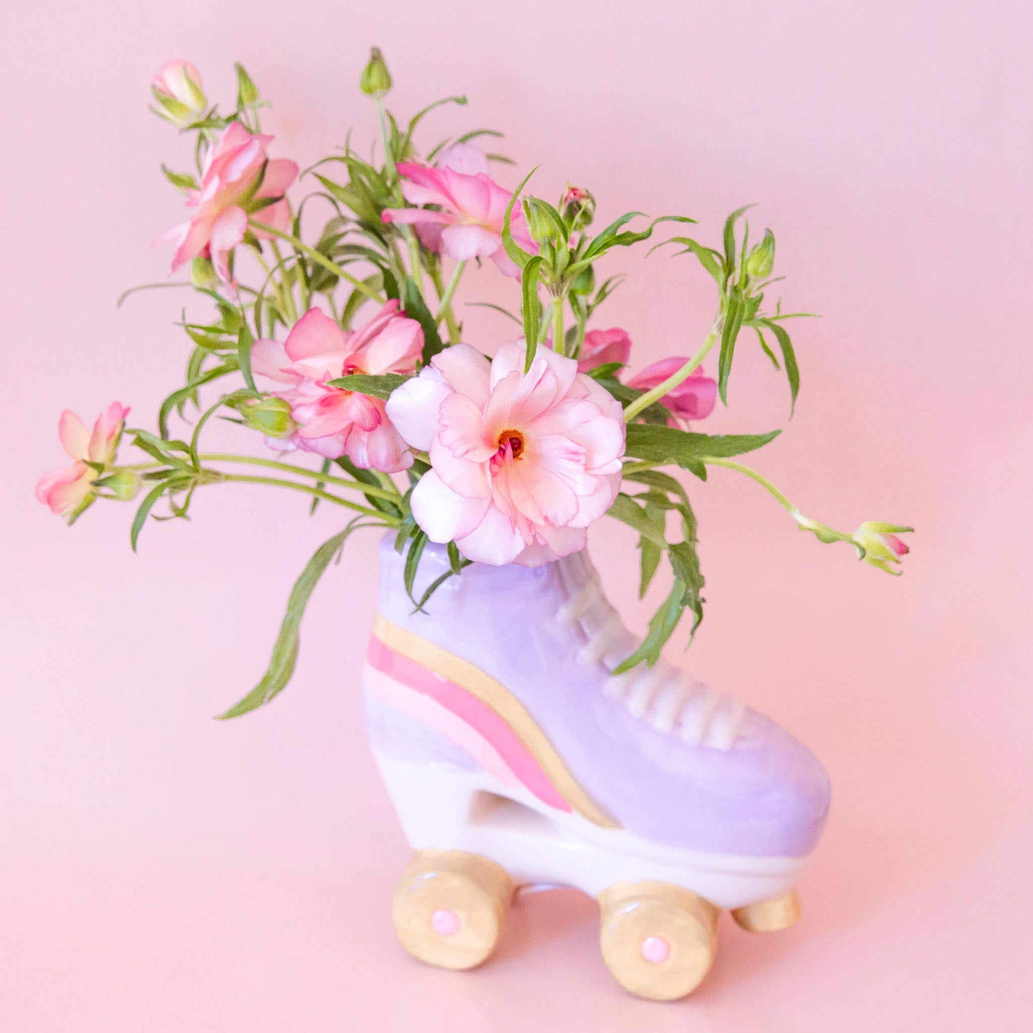 A purple ceramic roller skate shaped planter with yellow and pink details. Plants photographed not included with purchase