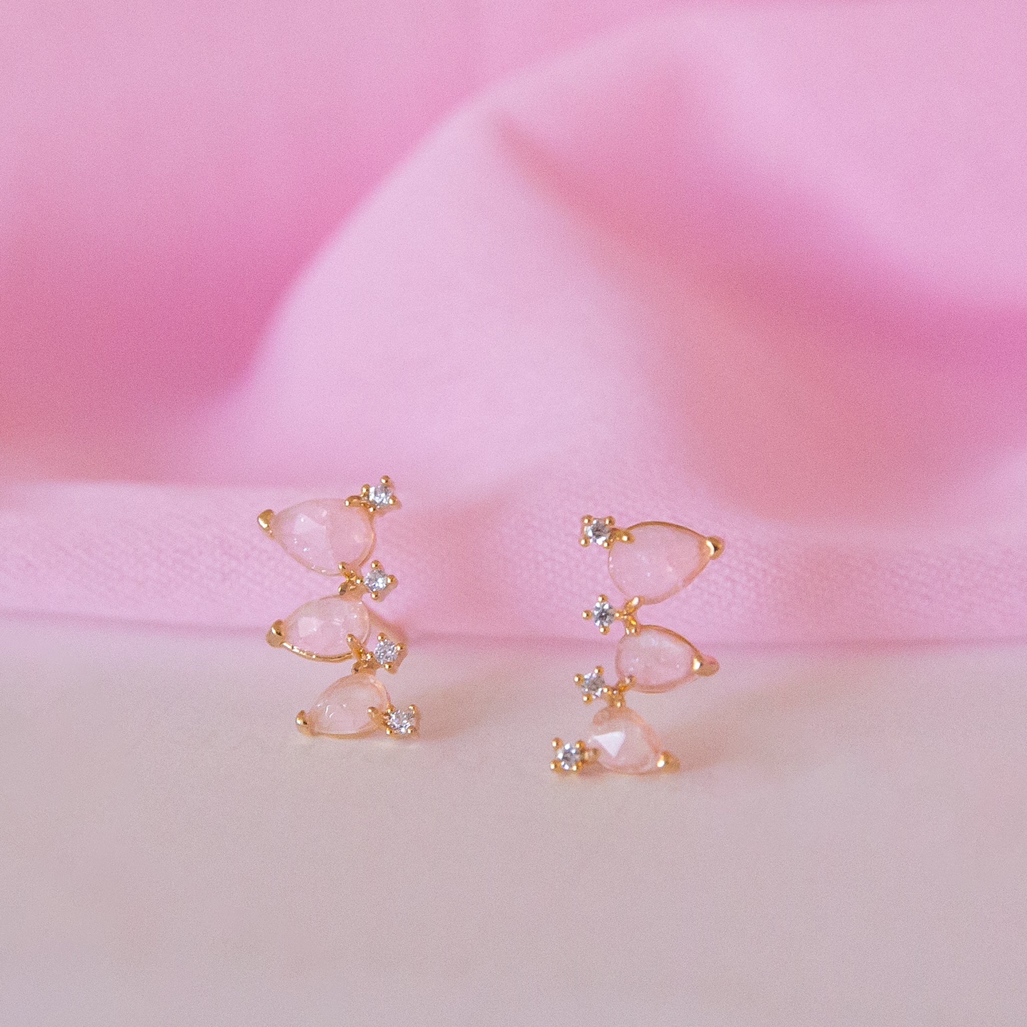 A pair of pink stud earrings with three teardrop shaped stones and cz accents.  