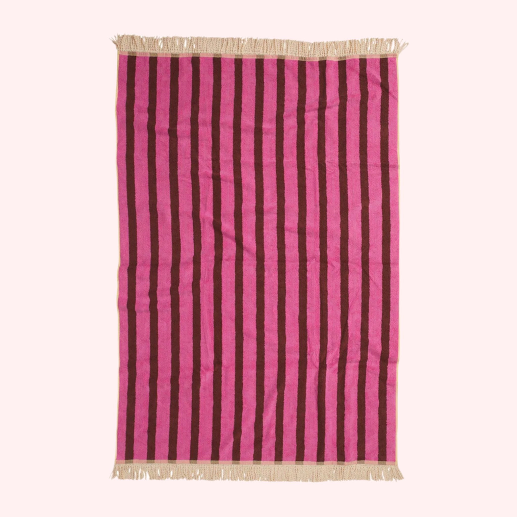 A pink chevron and striped print towel with an ivory tassel edge on two sides. 