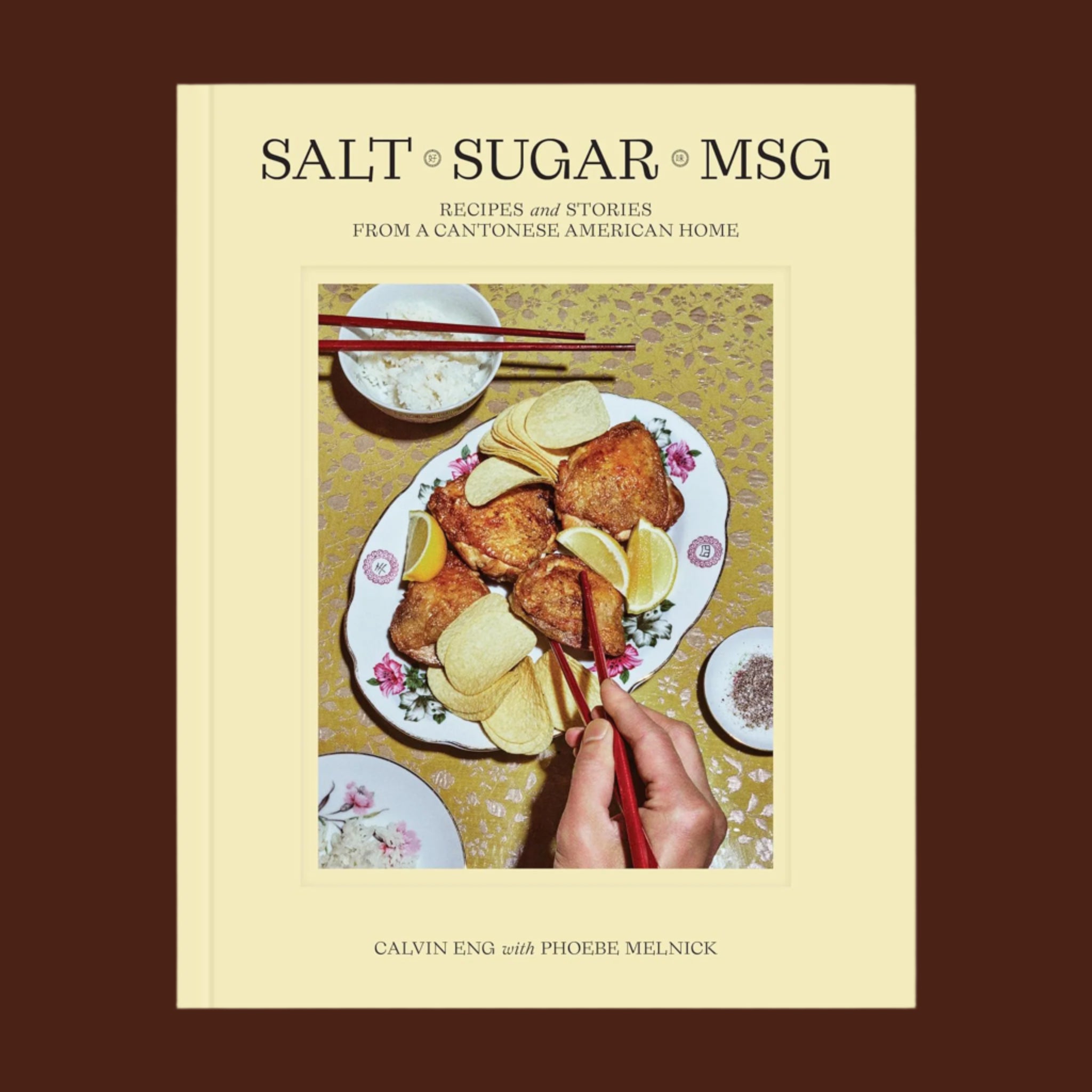 A book cover with plate full of food and pringle chips with a black title at the top that reads, 'Salt Sugar MSG Recipes and Stories From A Cantonese American Home'. 