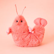 A pink shrimp shaped stuffed animal. 