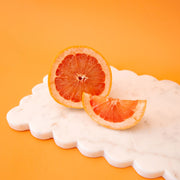 A white marble rectangle cutting board with a scalloped edge. 