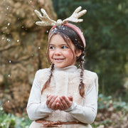 A pink velvet headband with sequin antler top. 