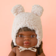 A white sherpa hat with ears on a Minikane doll. 