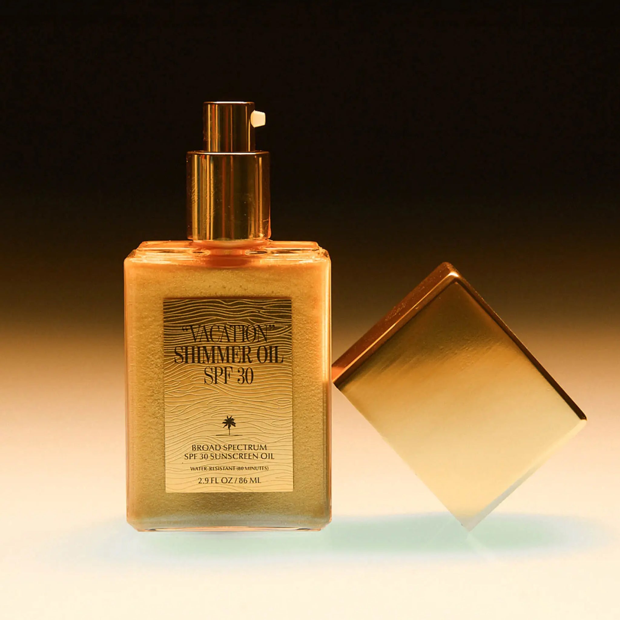 A glass bottle of shimmer body oil with gold flecks and a pump applicator.