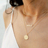 A model wearing the dainty gold chain necklace with a gold plated charm that reads, "sister". 