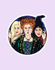 A round sticker with a graphic of the Sanderson sisters from Hocus Pocus. 
