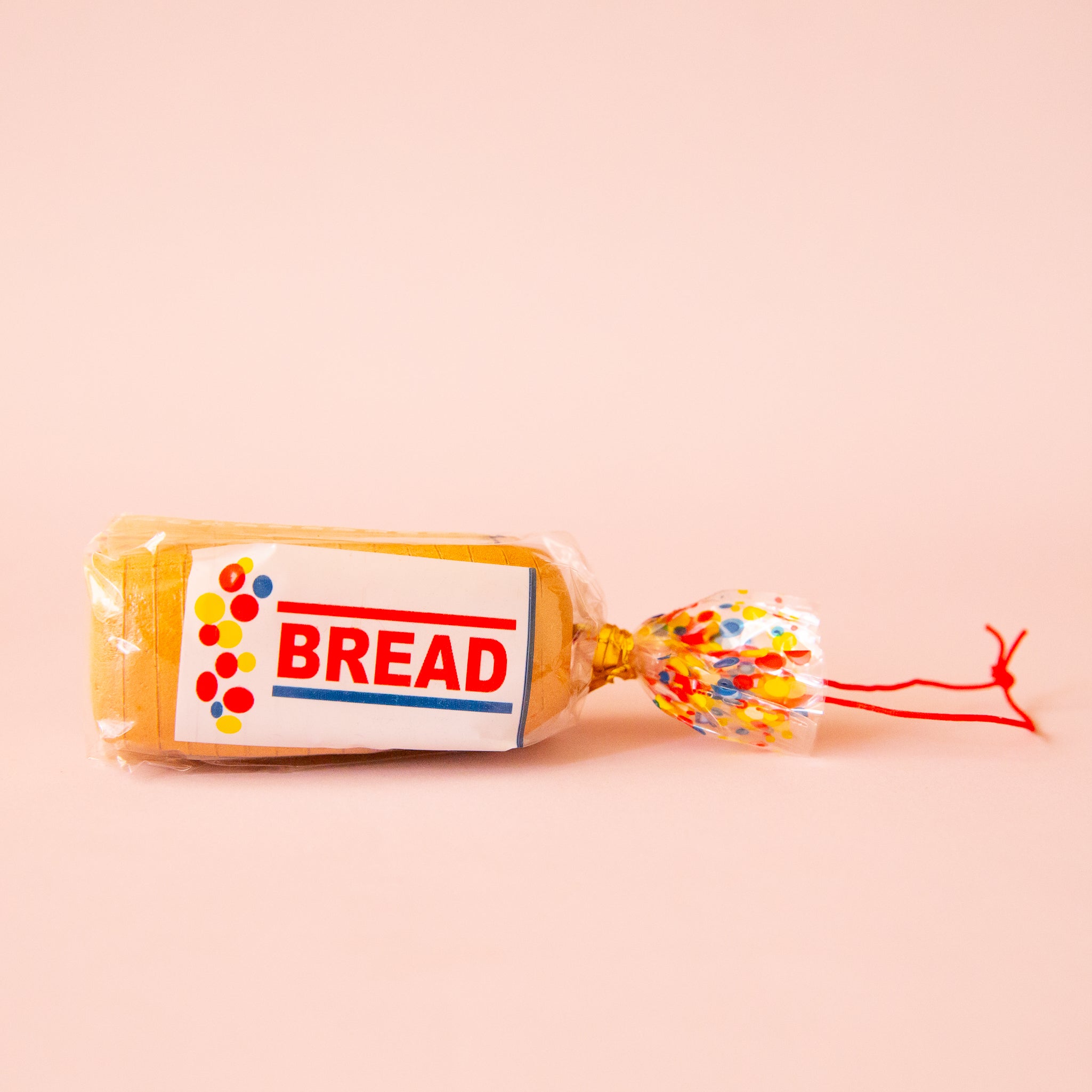 A sliced bread shaped ornament made of resin with a red loop for hanging. 