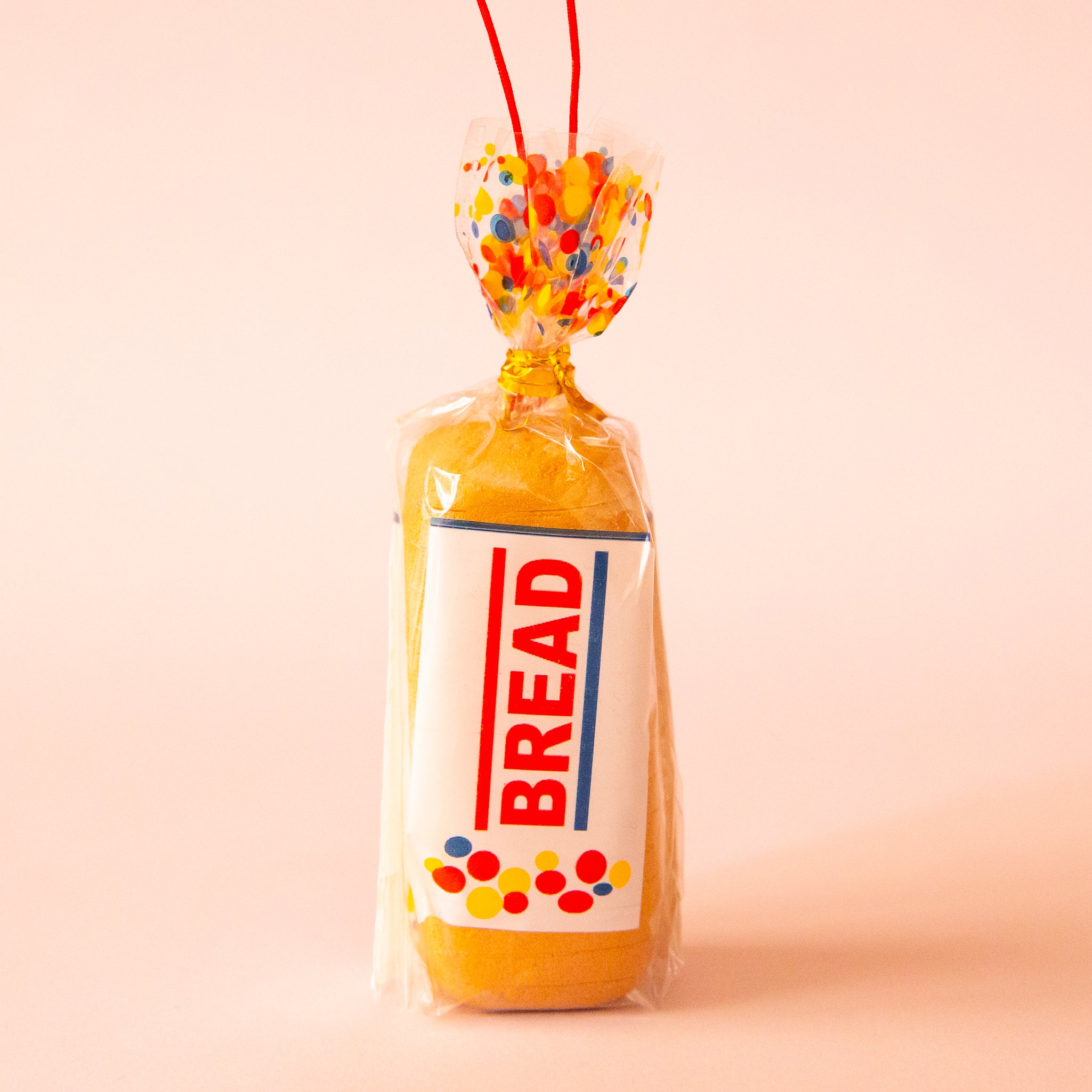 A sliced bread shaped ornament made of resin with a red loop for hanging. 