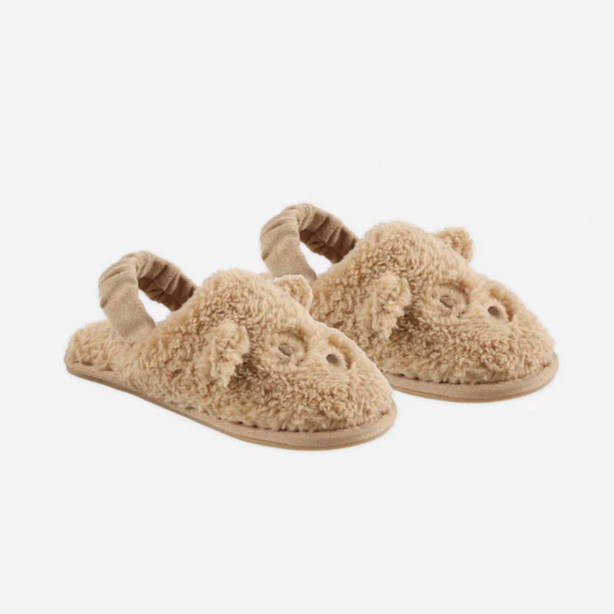 A pair of fuzzy brown slippers with a bear face design on the front and a strap on the back. 