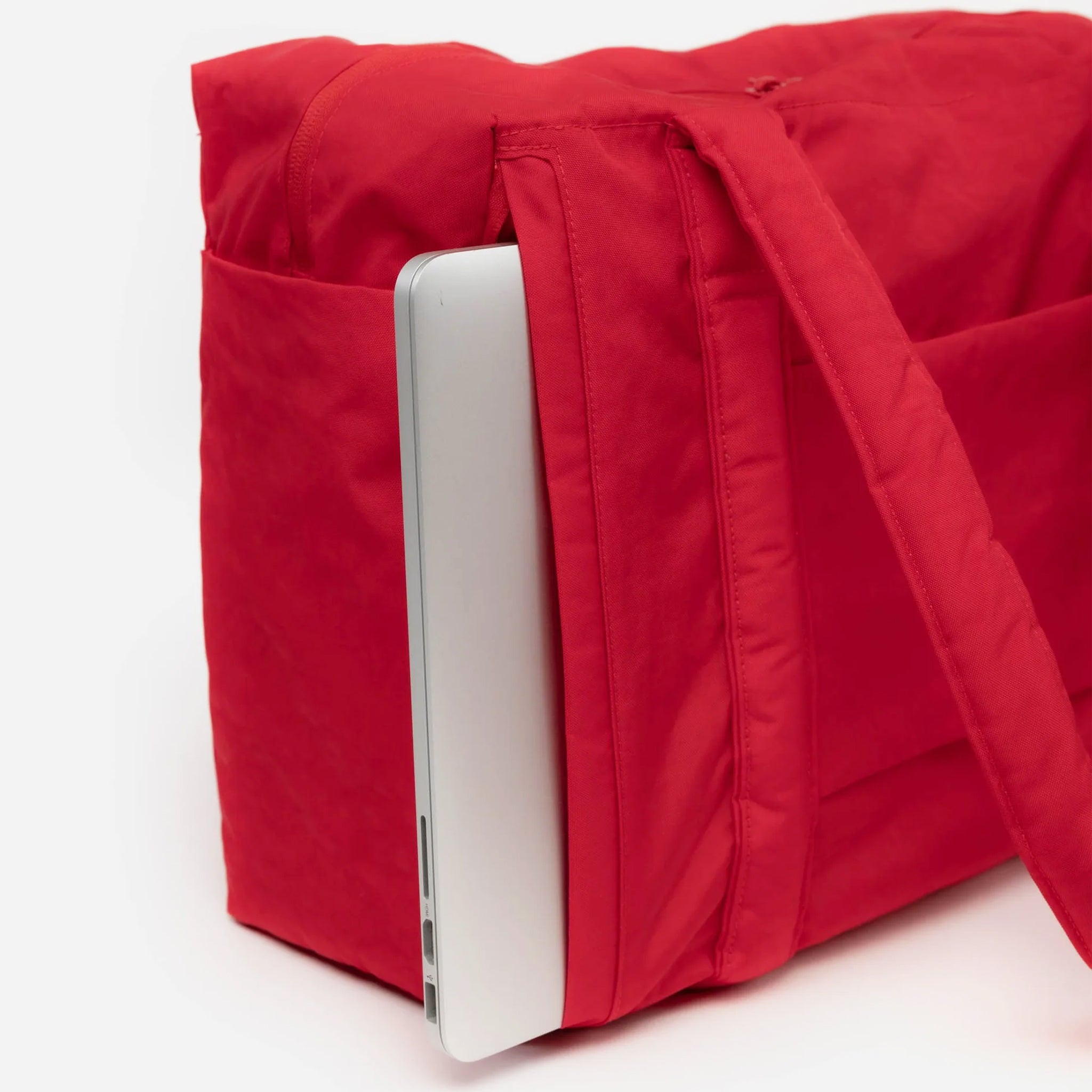 A red small carry on tote bag with two handle straps, front pockets and a zipper closure.