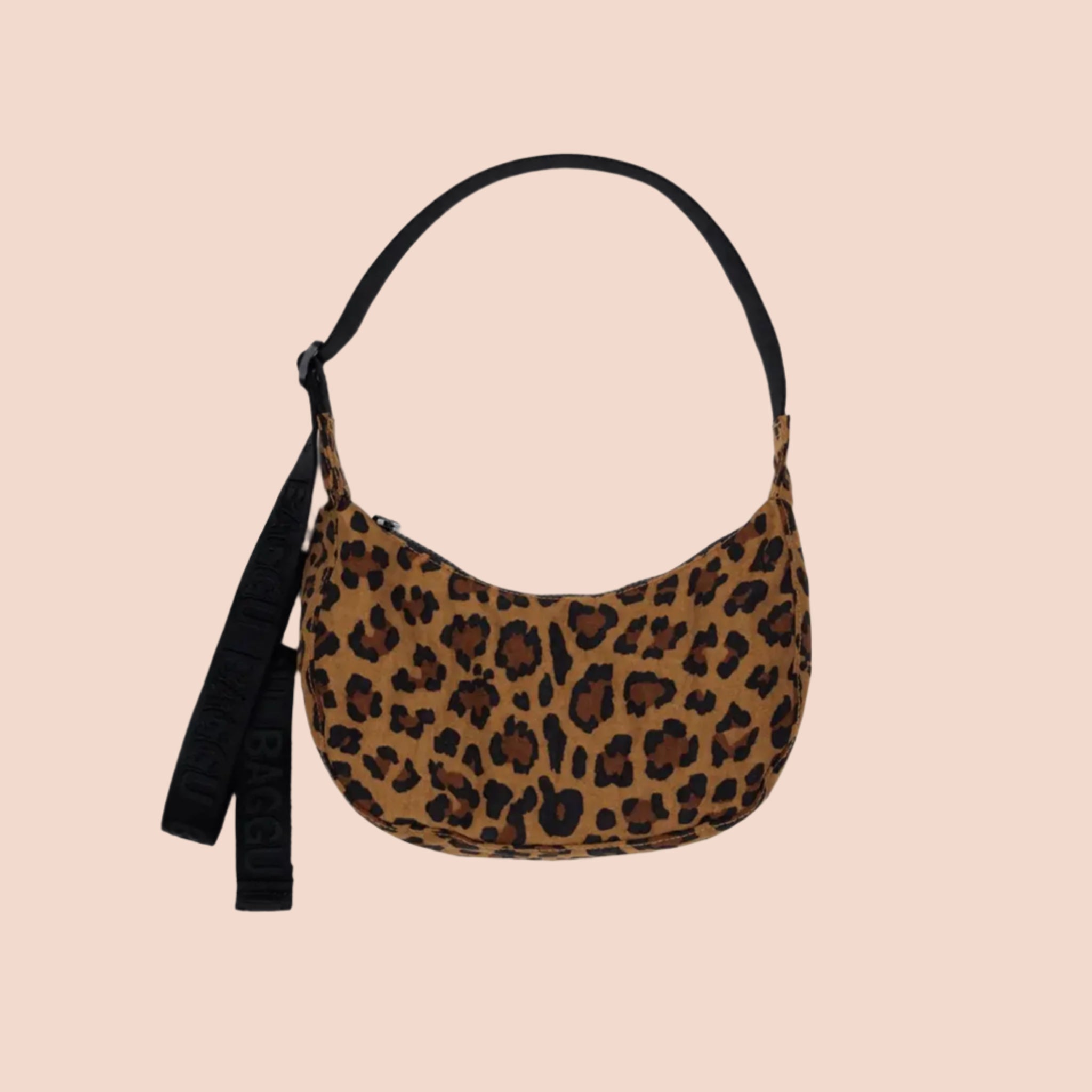 A leopard print curved crescent shaped handbag with a black strap that can adjust from a shoulder bag length to a crossbody. 