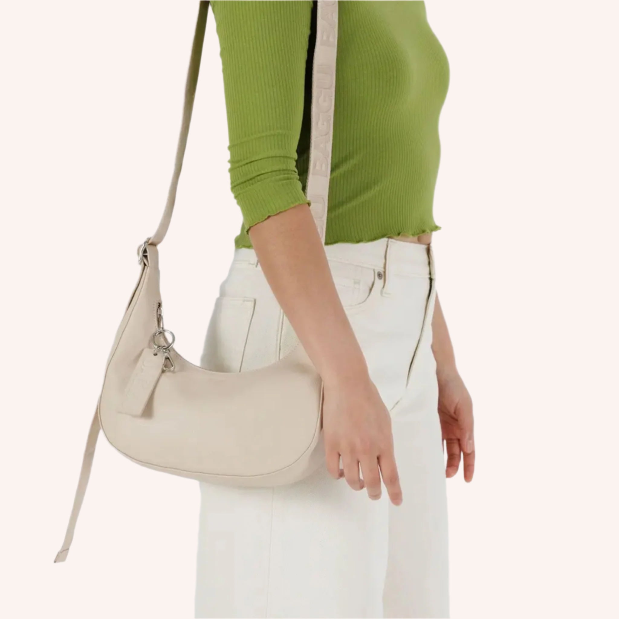 A small cream leather shoulder bag with an adjustable strap. 