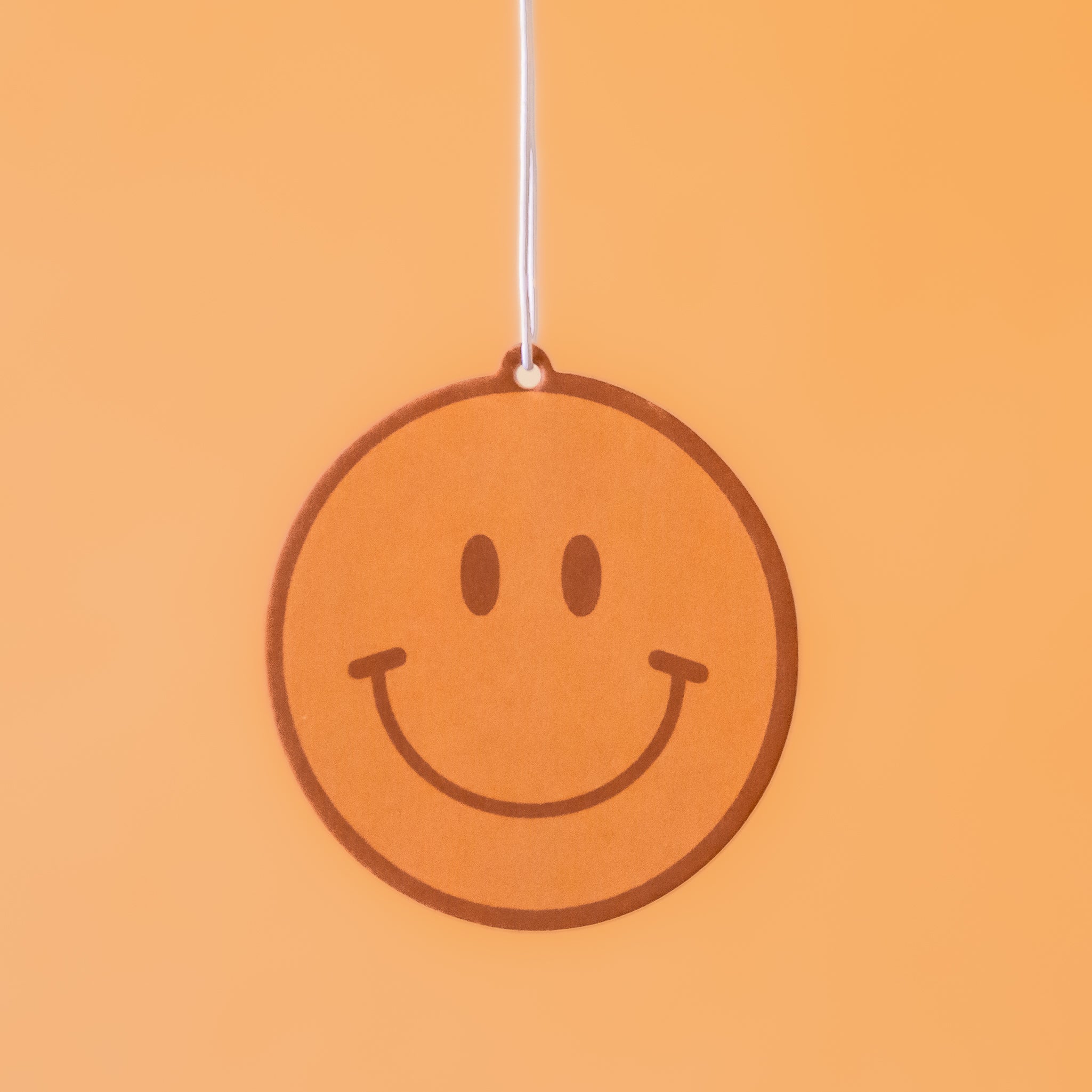 A yellow smiley face car air freshener.