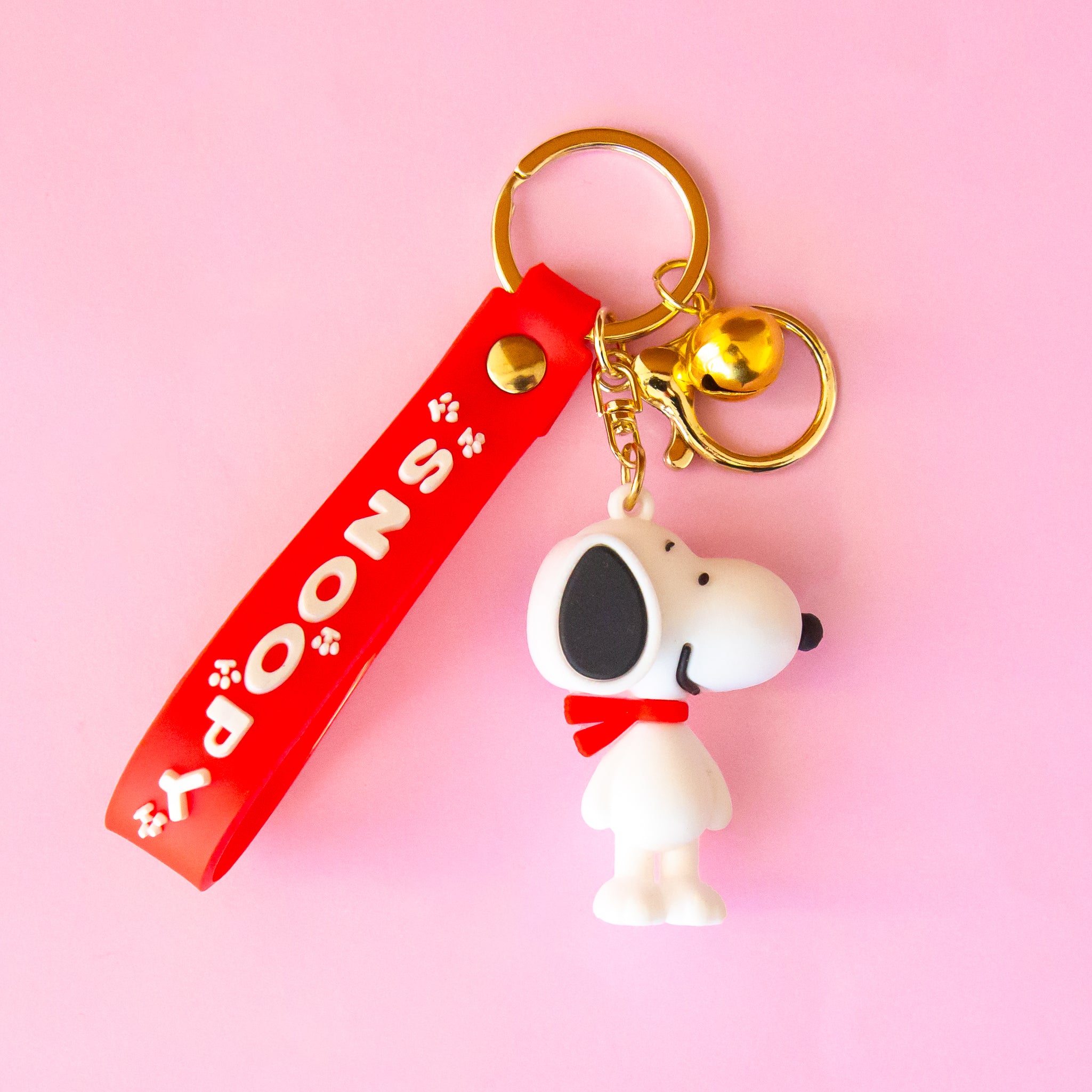 A snoopy shaped keychain with a red keychain detail that reads, &#39;Snoopy&#39;. 