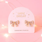 A pair of gold and pink bow shaped earrings with small baguette shaped stones.