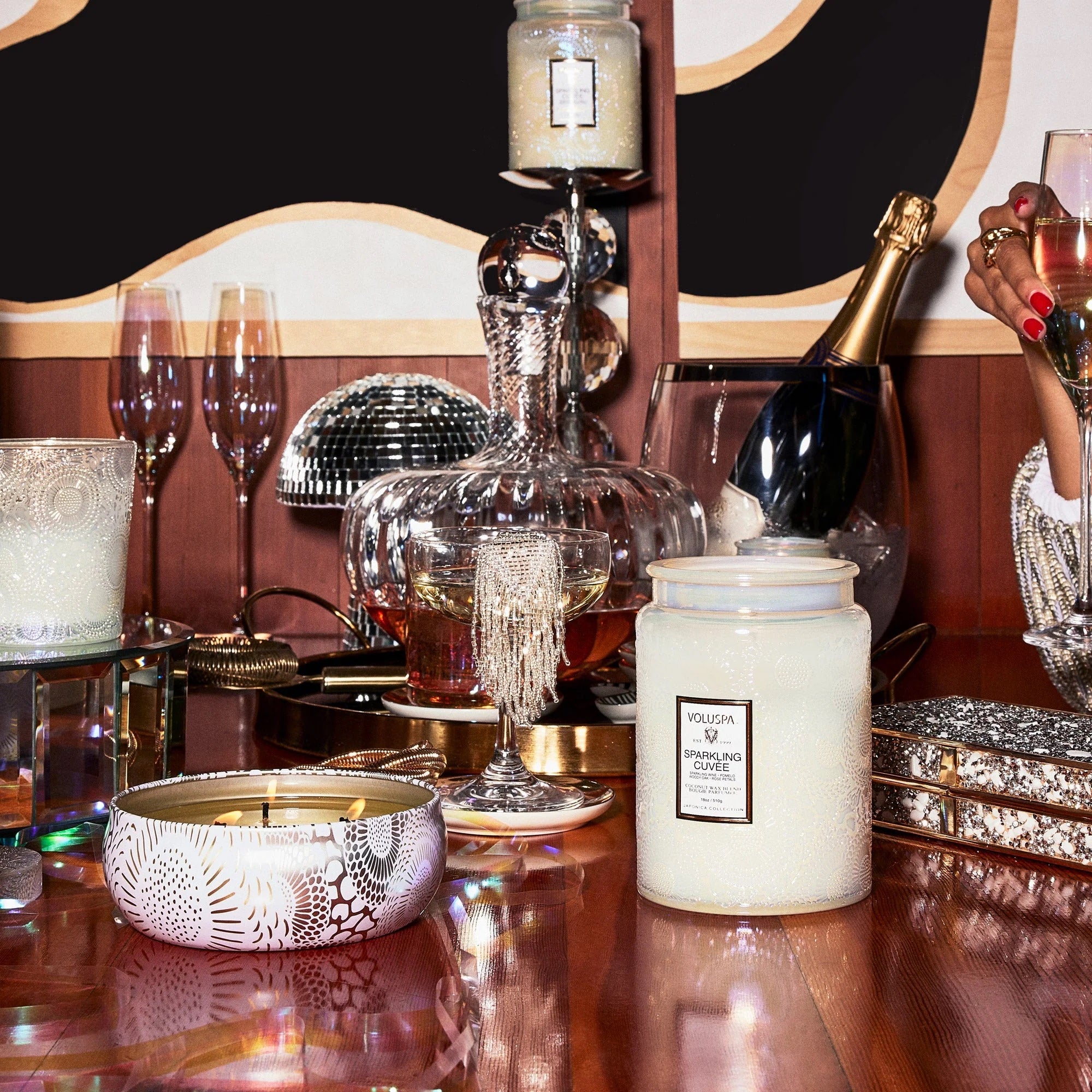 A white glass decorative candle jar with the classic Voluspa logo in the center that says the scent of the candle which in this case is &quot;Sparkling Cuvee&quot;.