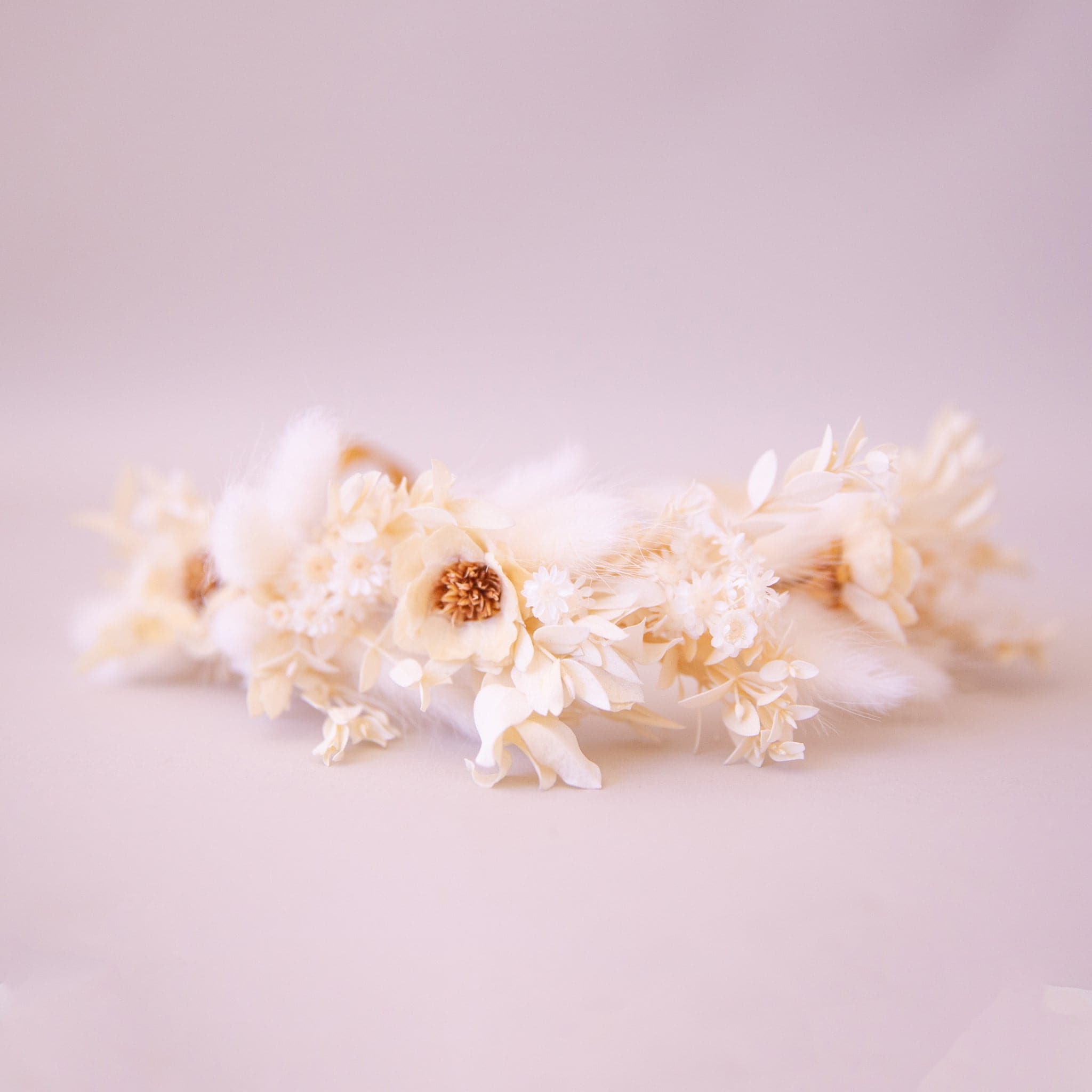 A flower crown made up of neutral dried florals and a tie detail at the back. 