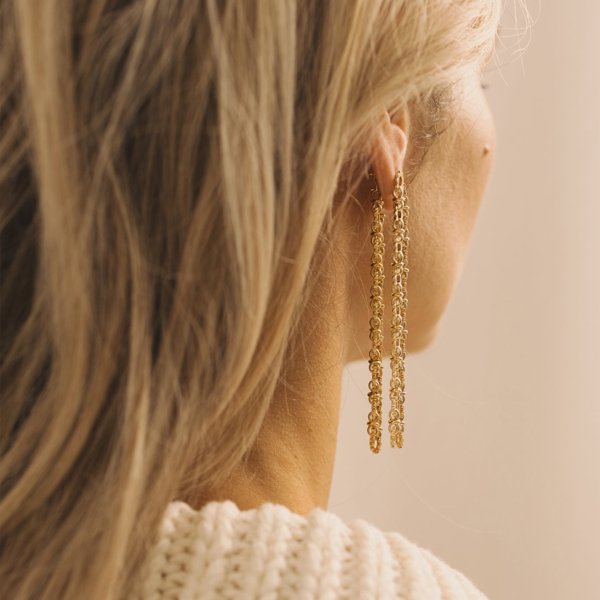 A pair of dangle chain earrings that have a sun shaped chain link. 