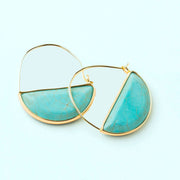 In front of a cream background is a pair of gold earrings. The top is a thin gold hoop. The bottom is a turquoise half circle with a gold border.