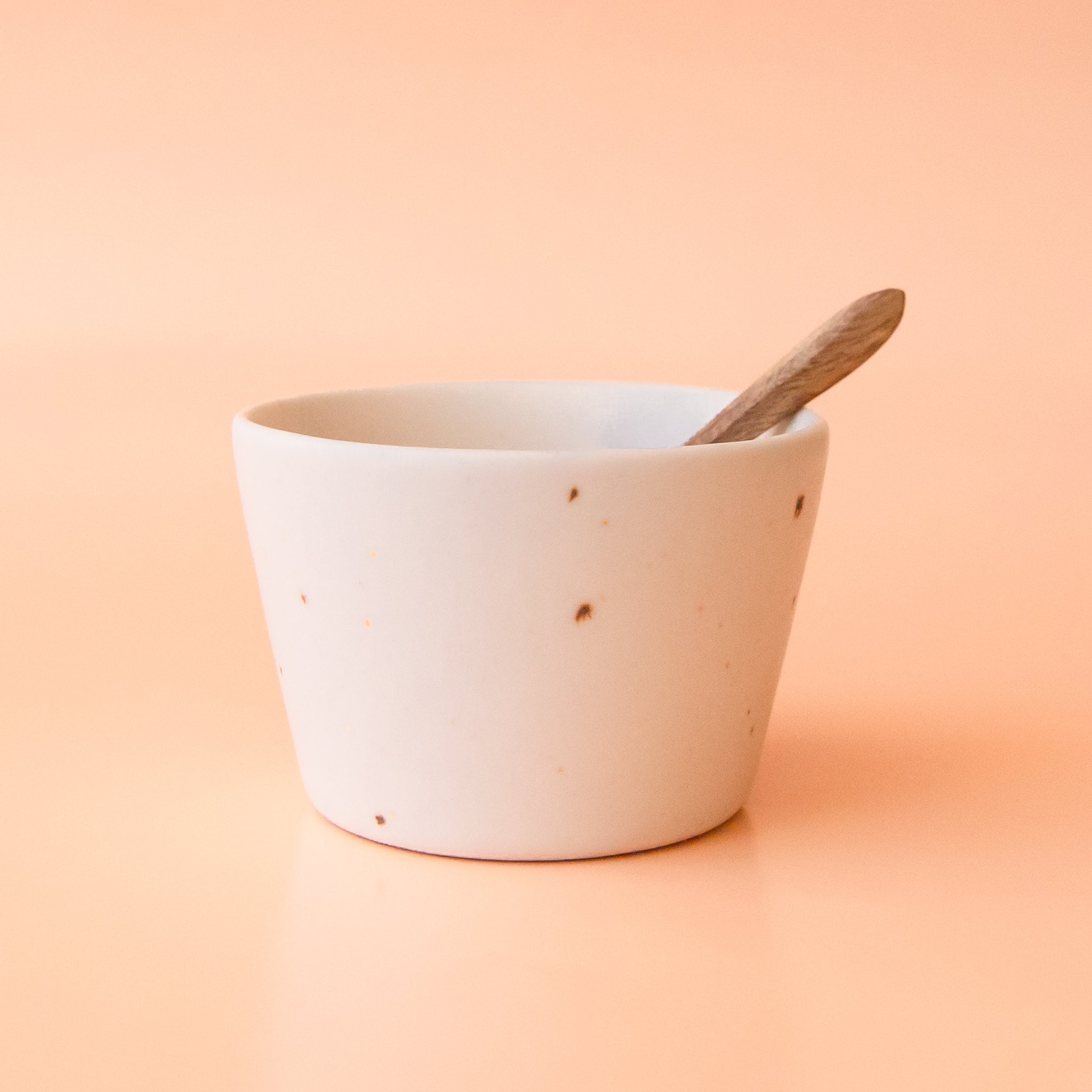 A neutral stoneware bowl with a tiny wooden spoon. 