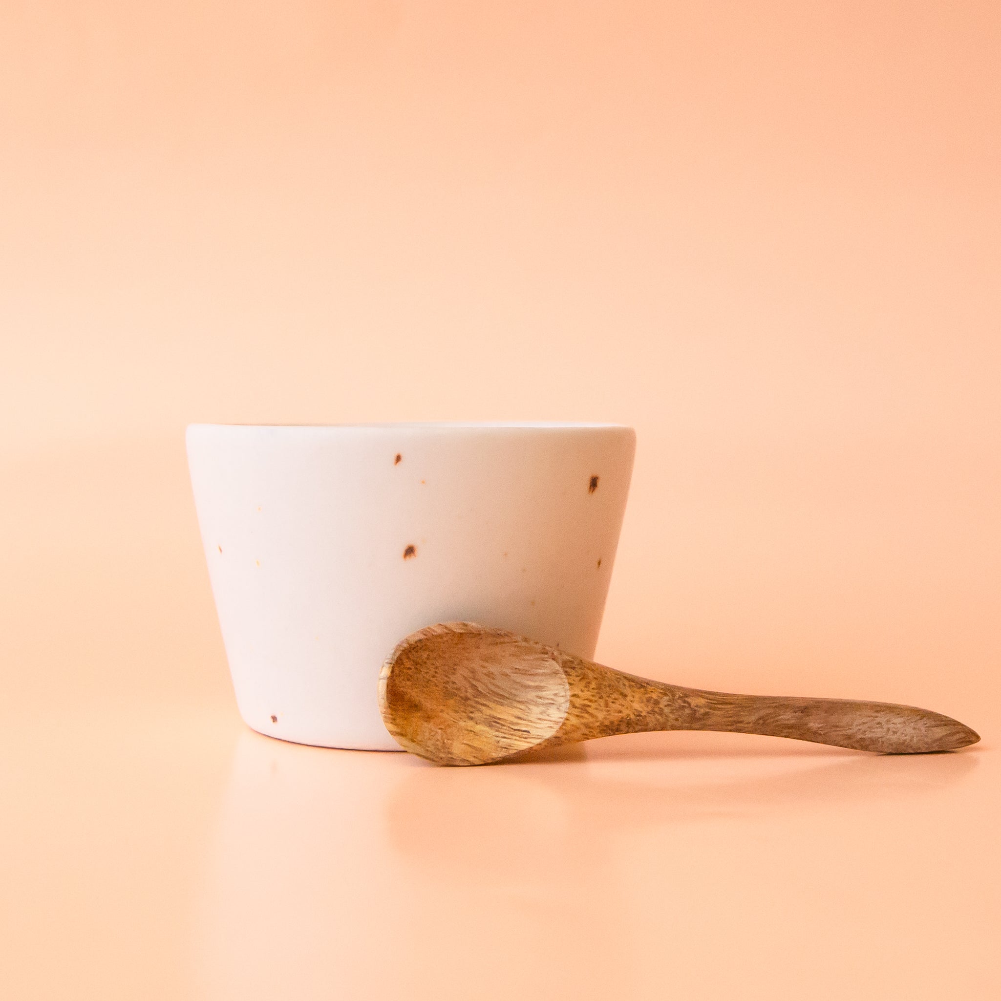 A neutral stoneware bowl with a tiny wooden spoon. 