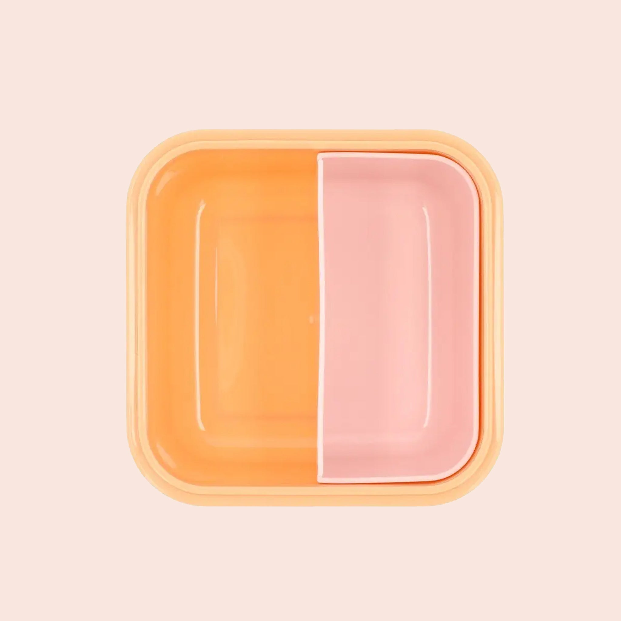 The interior of the lunch box with pink and orange compartments. 