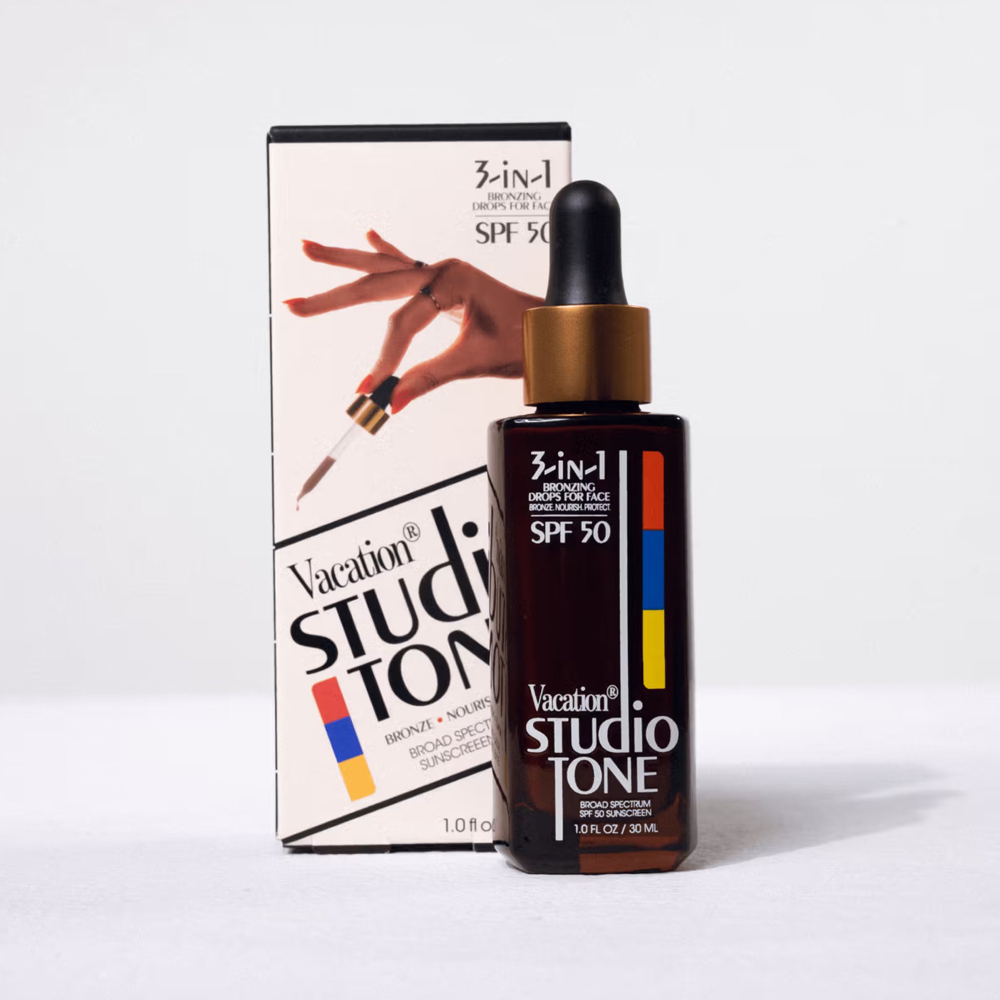 A dropper style bottle of bronzing drops with text that reads, '3-in-1 SPF 50 Vacation Studio Tone'. 