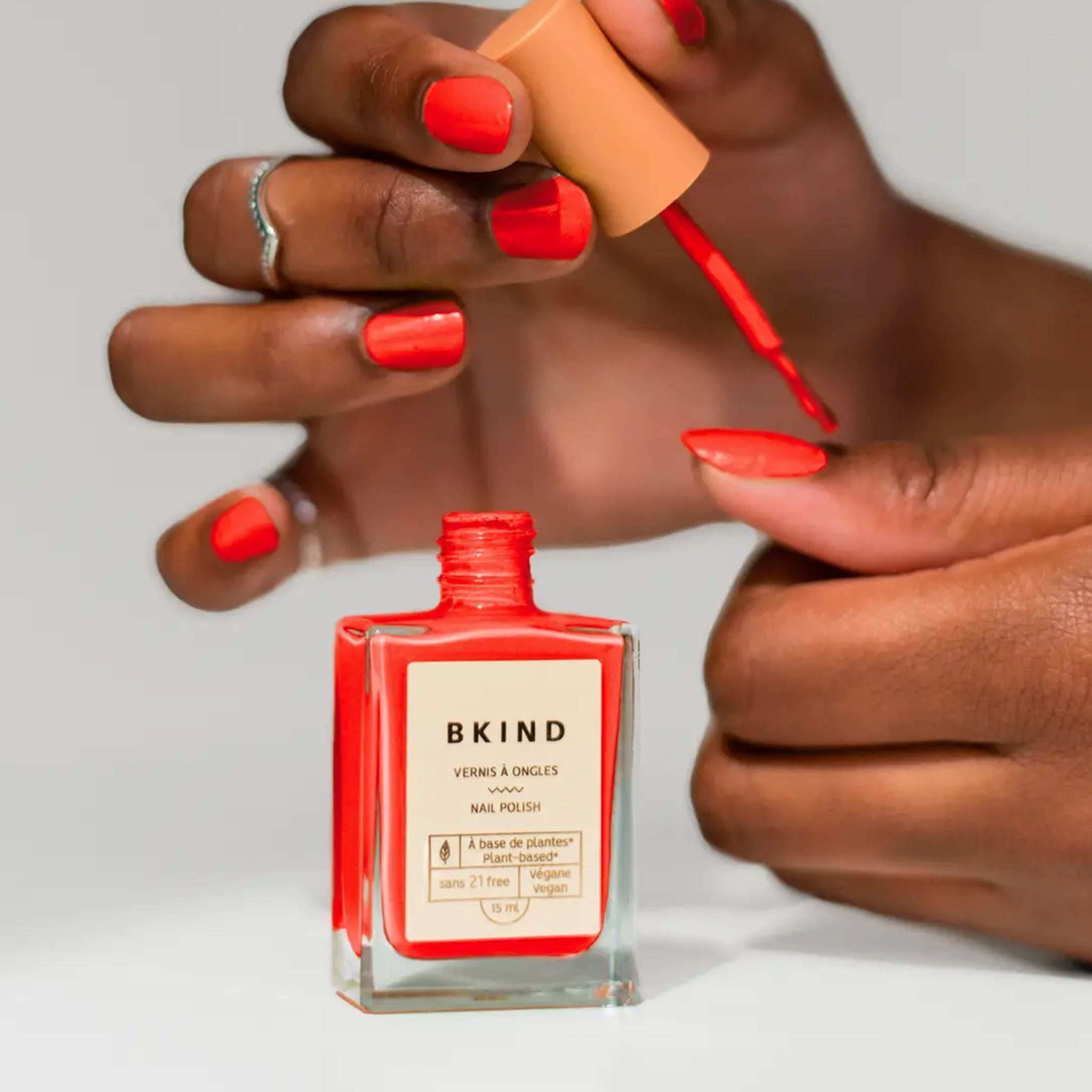 A bright red nail polish in a rectangle glass bottle.