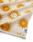 A cream and mustard yellow beach / bath towel with a sun design on the front and back.