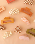 On a peachy background is an assortment of claw clips in different shapes and sizes. 