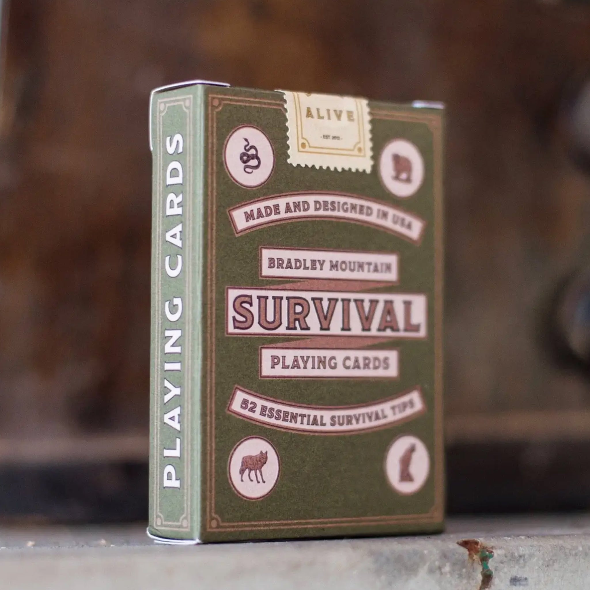 A deck of playing cards in a green box with a survival tip on each card. The box reads, 'Made and Designed in the USA Bradley Mountain Survival Playing Cards 52 Essential Survival Tips'. 