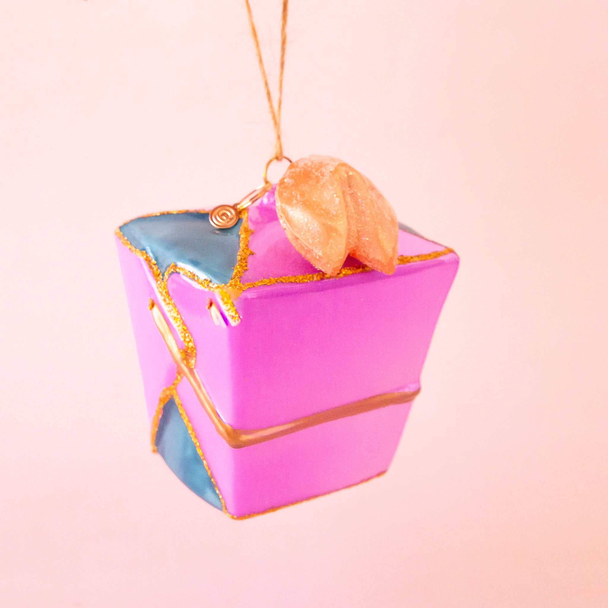 A glass ornament in the shape of a purple takeout box. 