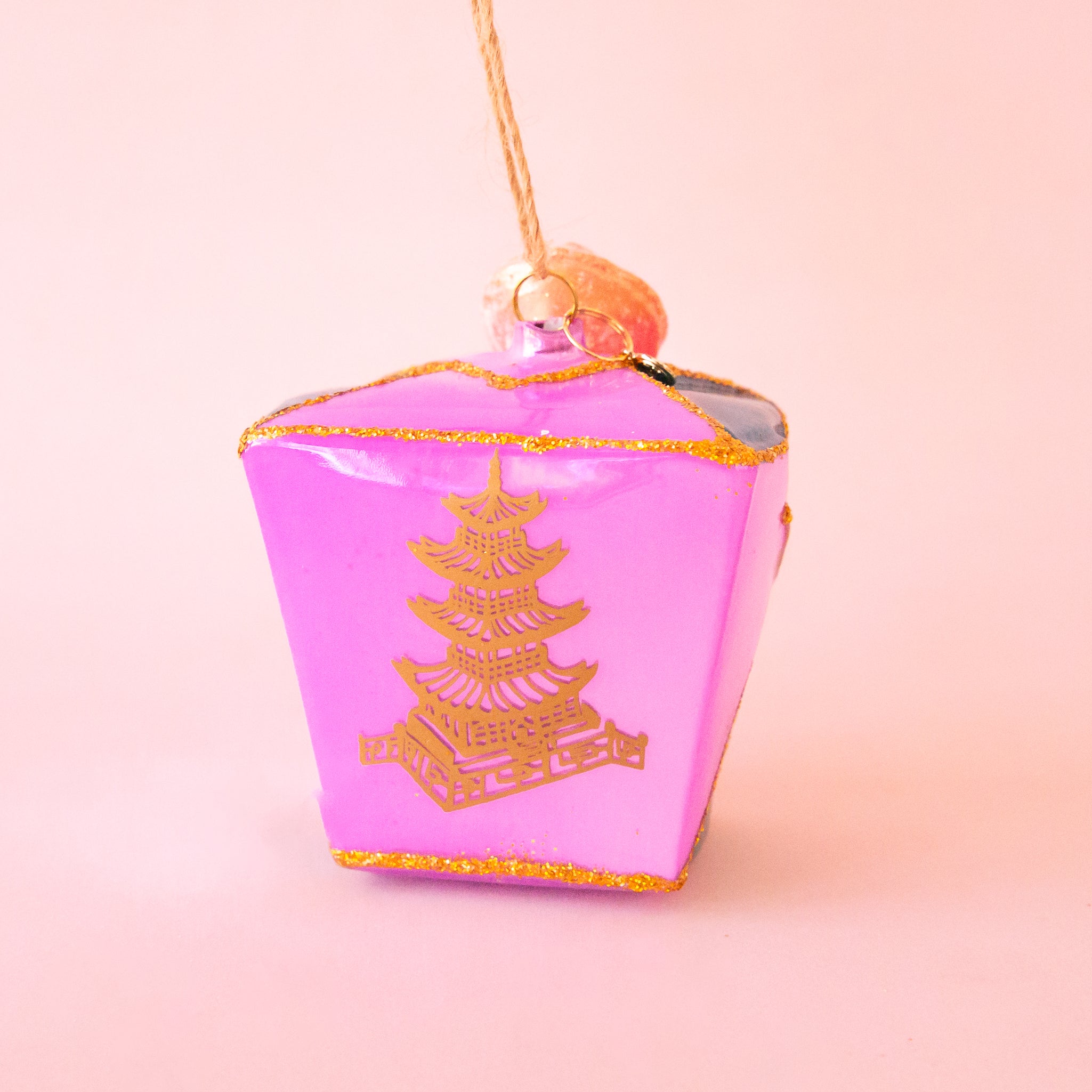 A glass ornament in the shape of a purple takeout box. 