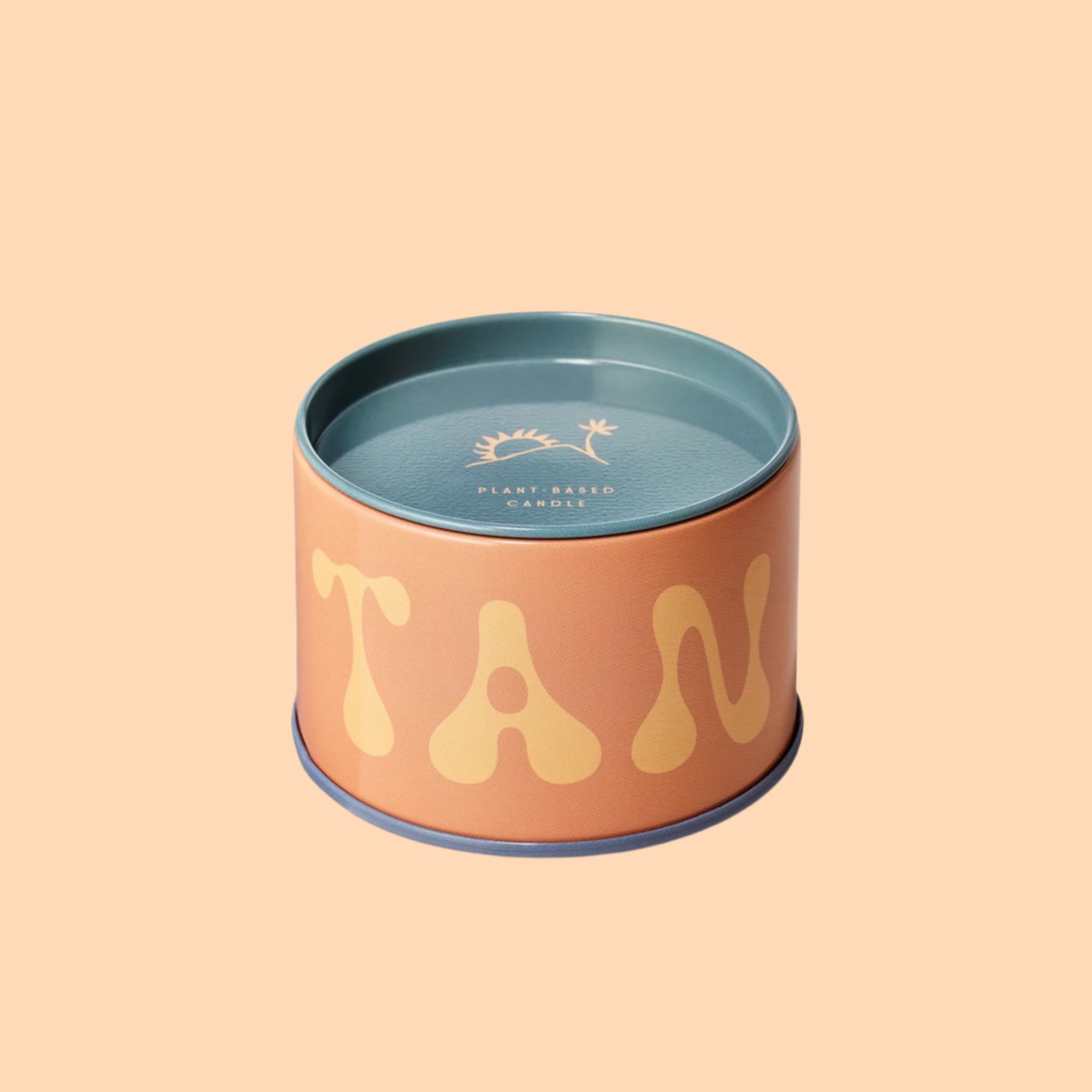 A blue and orange metal tin candle with text that reads, 'TAN'. 