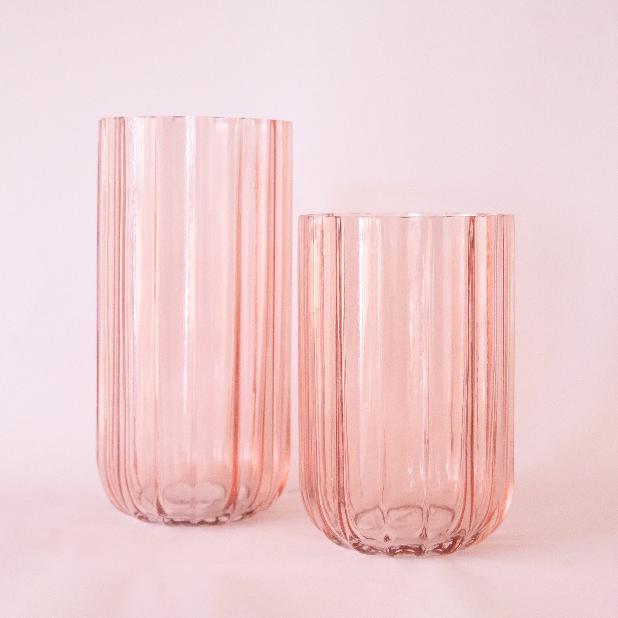 Two pink glass vases in different sizes. 