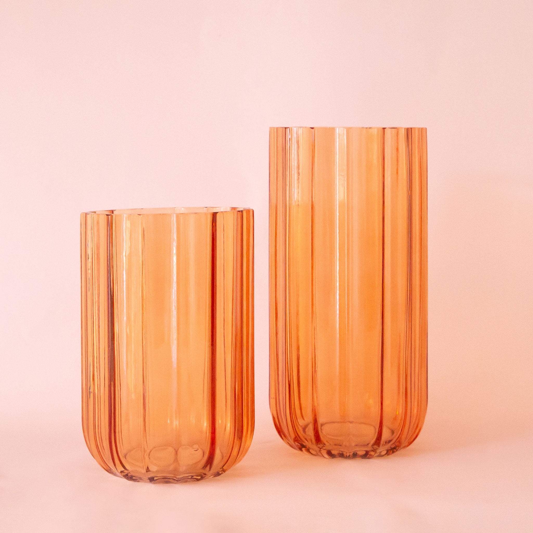 Two different sized glass vases with a translucent orange shade.  