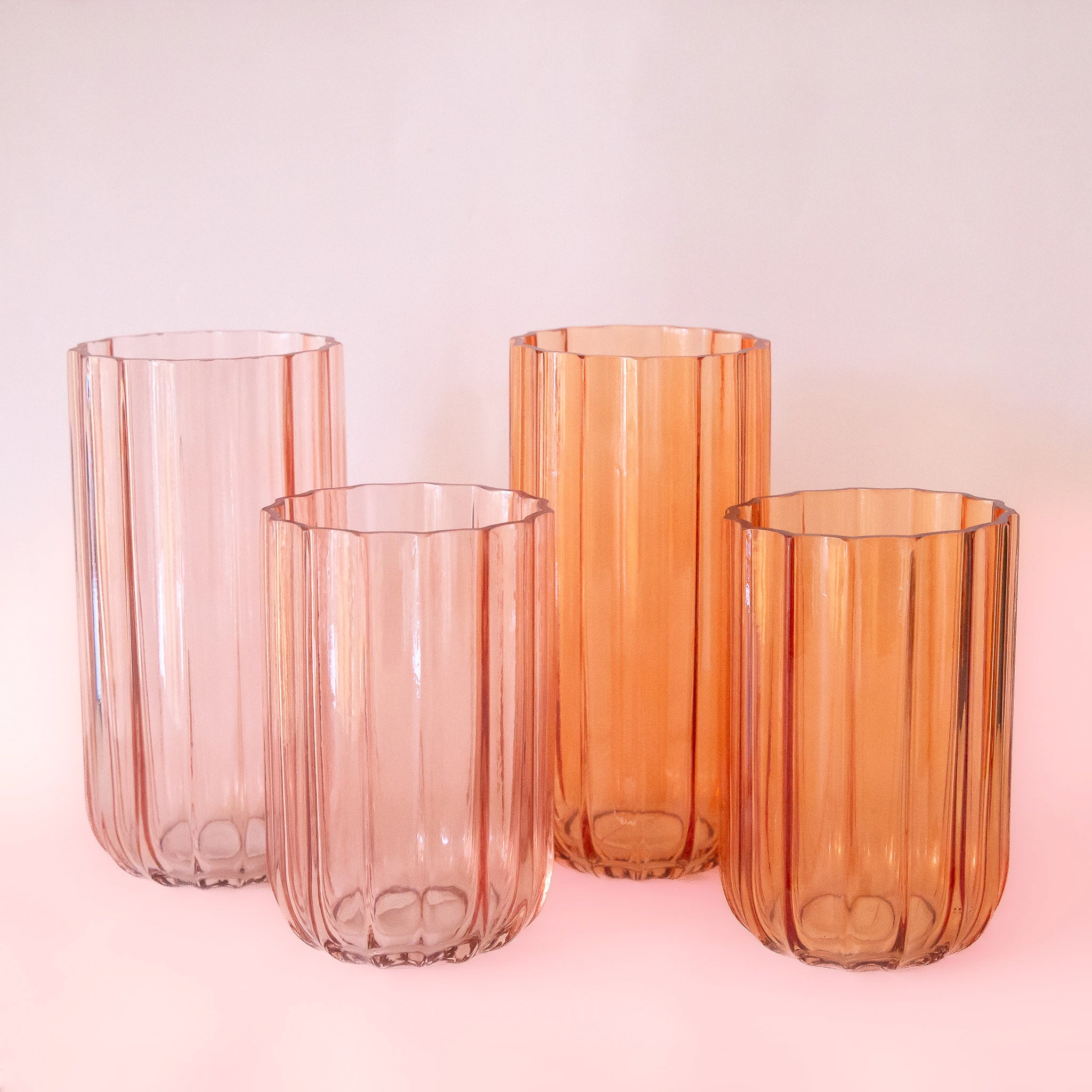 Four glass vases in orange and pink shades with two different sizes. Each vase sold separately. 