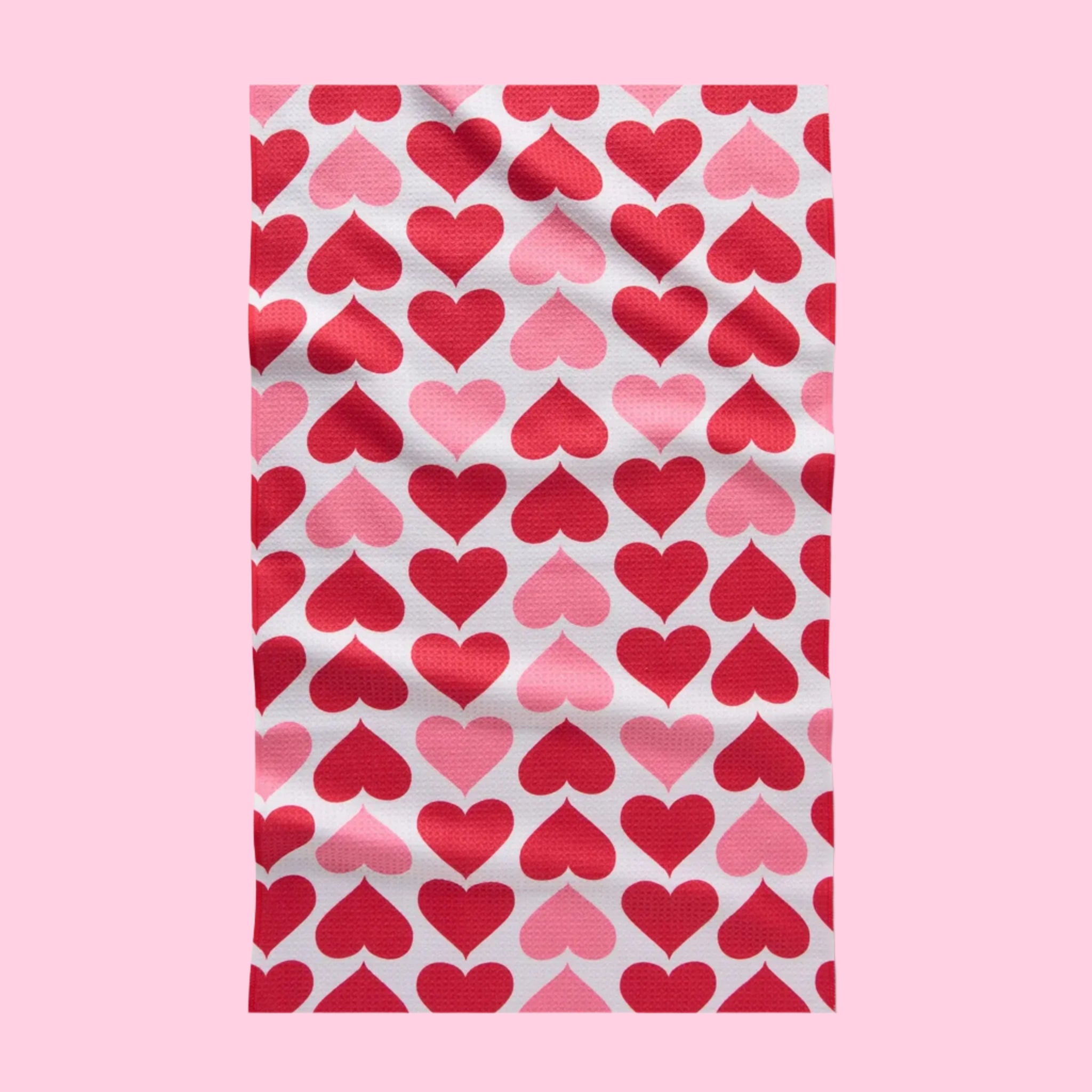 A one side printed waffle knit tea towel with a pink and red heart pattern. 