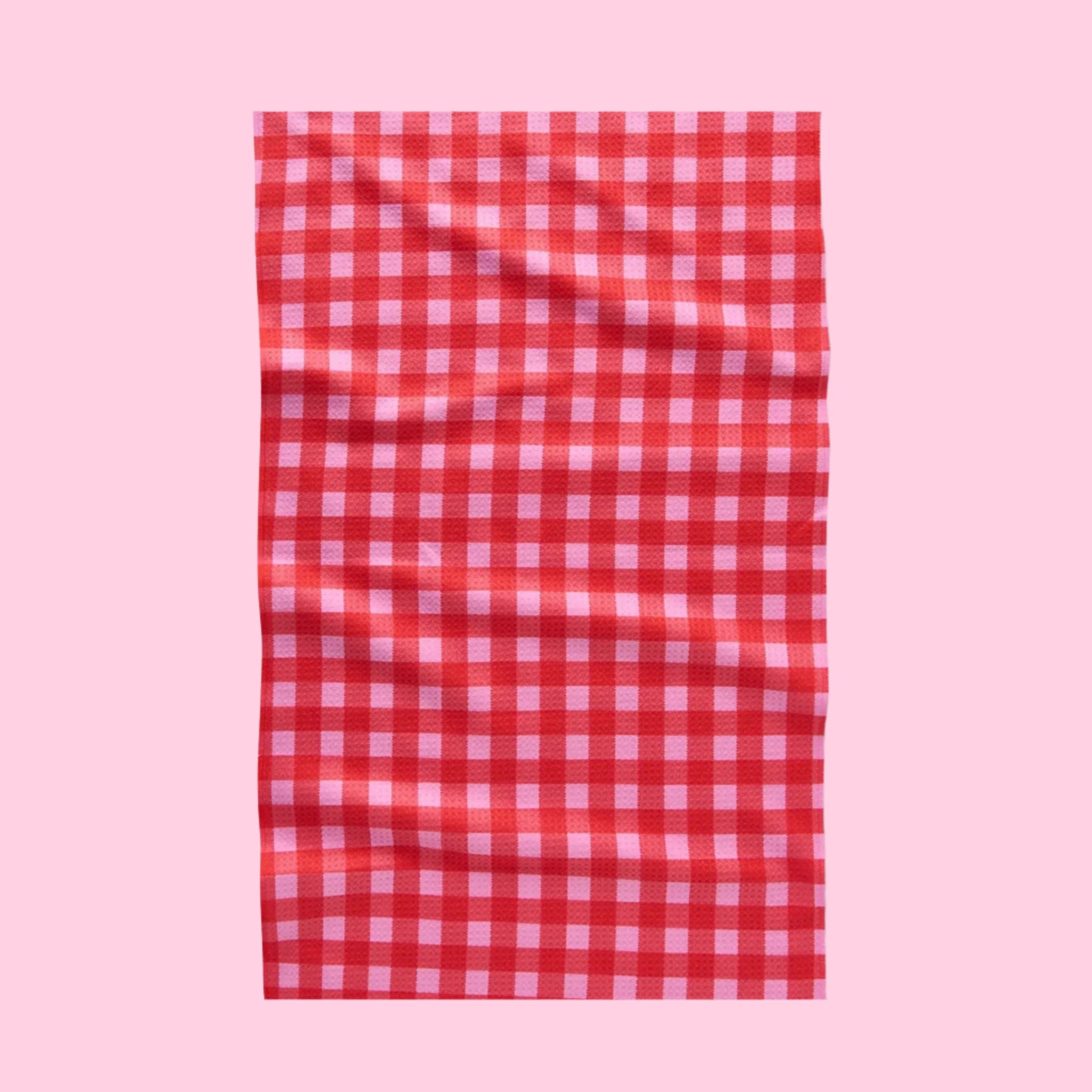 A red and pink gingham print tea towel with a waffle weave.