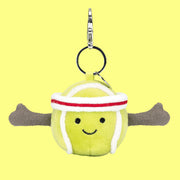 On a green background is a green tennis ball shaped bag charm with a smiling face and a silver loop for attaching.