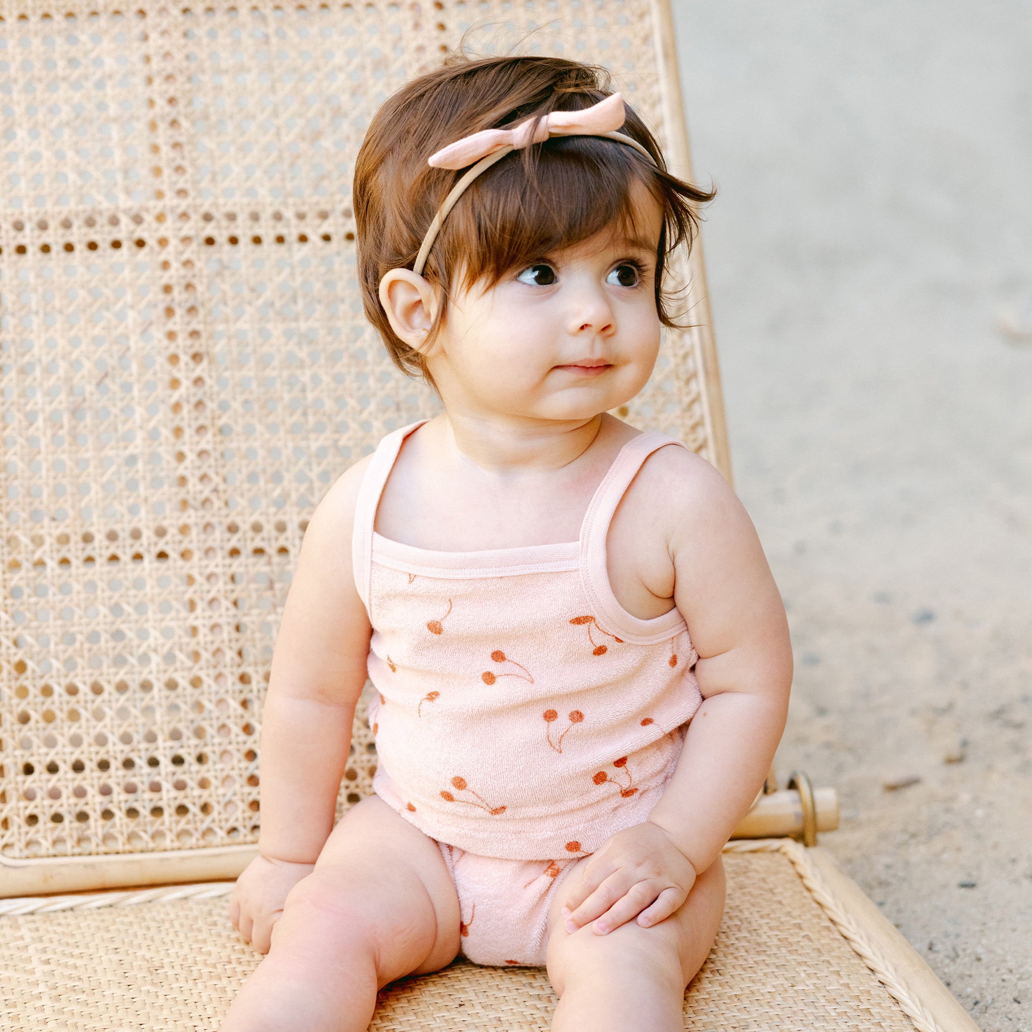 A spaghetti strap light pink terry cloth jumpsuit with a cherry print. 