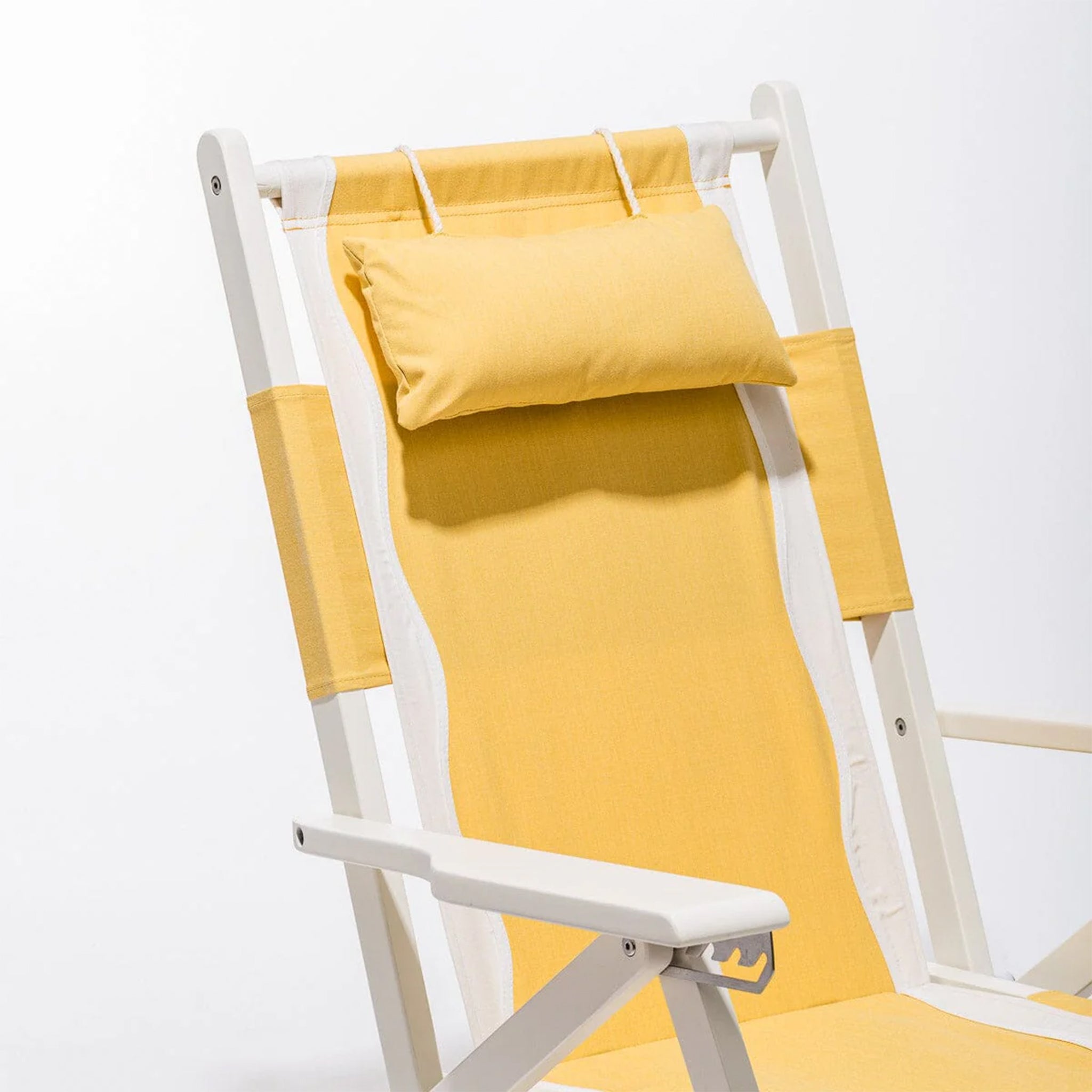 A white and yellow folding beach chair with a zip back pocket and a headrest pillow.